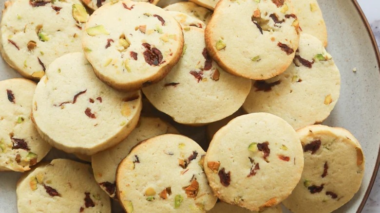 Cranberry pistachio cookies sliced into discs stacked on a beige plate