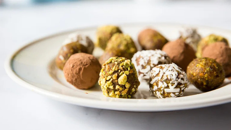 Date and pistachio bite balls coated in cocoa, pistachios, and coconut arranged on white plate