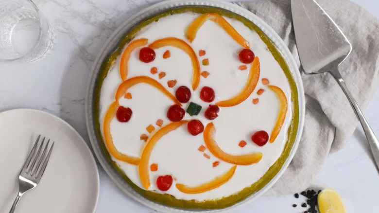 Traditional Sicilian cassata with fruit design on top served on a white plate and a white tablescape