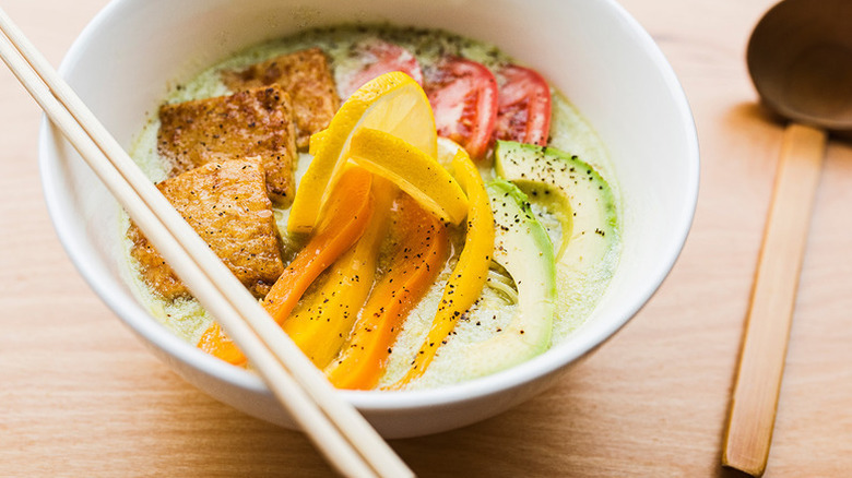 Bowl of vegan ramen with orange bell pepper, tofu, and avocado