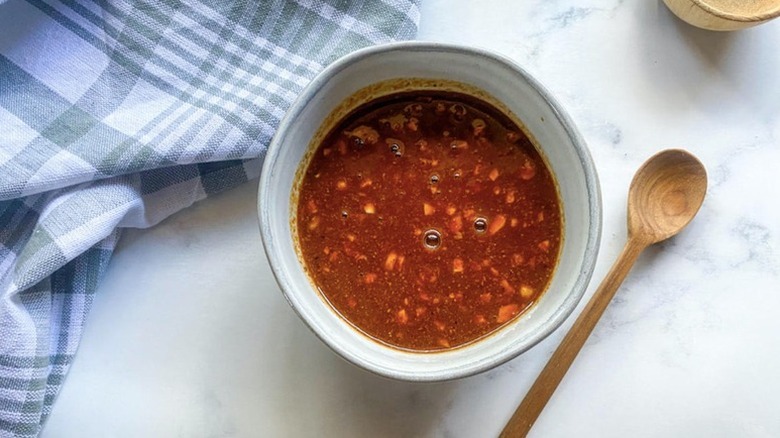 Bowl of hoisin sauce next to wooden spoon and blue linen