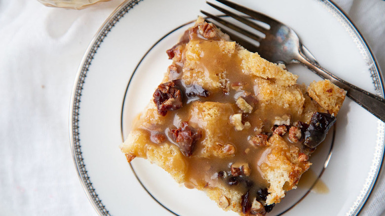 Slice of cherry pecan bread pudding on plate with fork