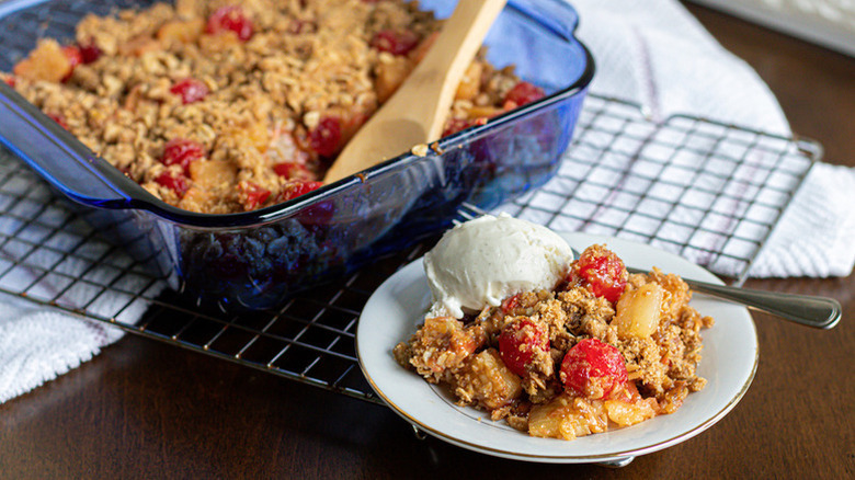 Pineapple cherry crisp served into dish with scoop of vanilla ice cream