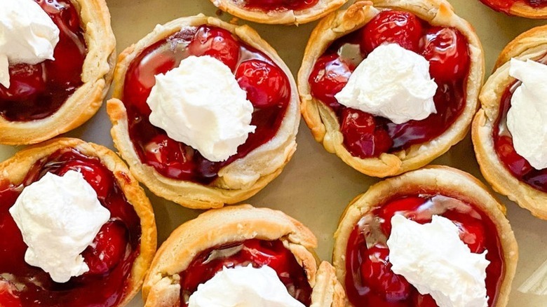 Mini cherry pies topped with whipped cream