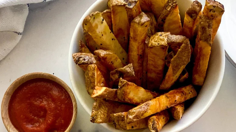 20-Minute Air Fryer French Fries in white bowl with small bowl of ketchup