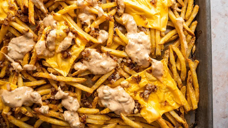Top view of copycat animal style fries on metal tray with a lot of cheese and sauce