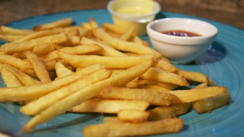 Copycat McDonald's fries served on blue plate with sauces in the back