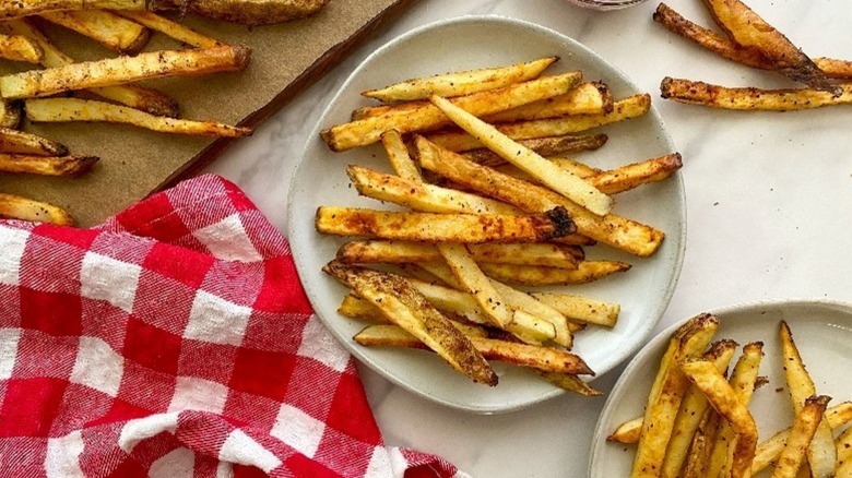 Top view of air fryer fries on a tray with more served on a plate next to it