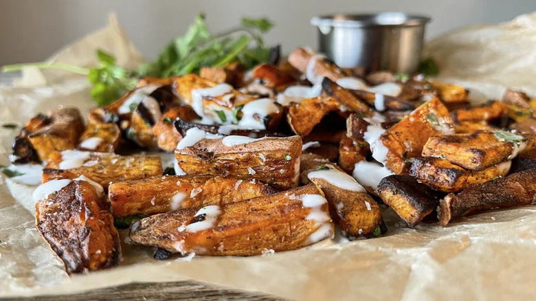 Sweet potato truffle fries arranged on parchment paper drizzled with a white sauce