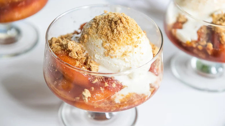 Peach crumble in dessert glass with scoop of ice cream