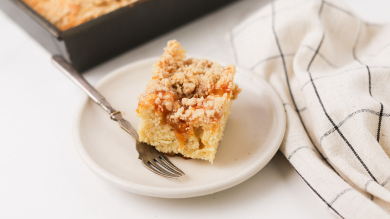 Slice of peach coffee cake on plate with fork