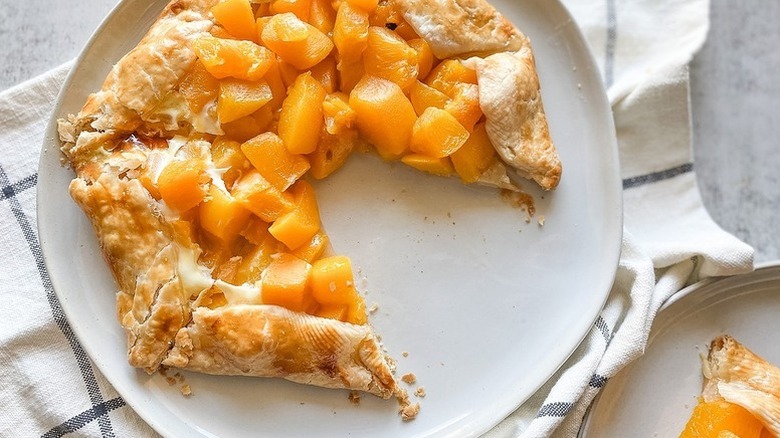 Peach tart on serving plate, with slice taken out