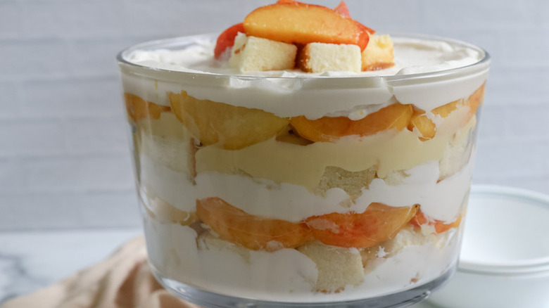 Layered peaches and cream trifle in glass serving bowl