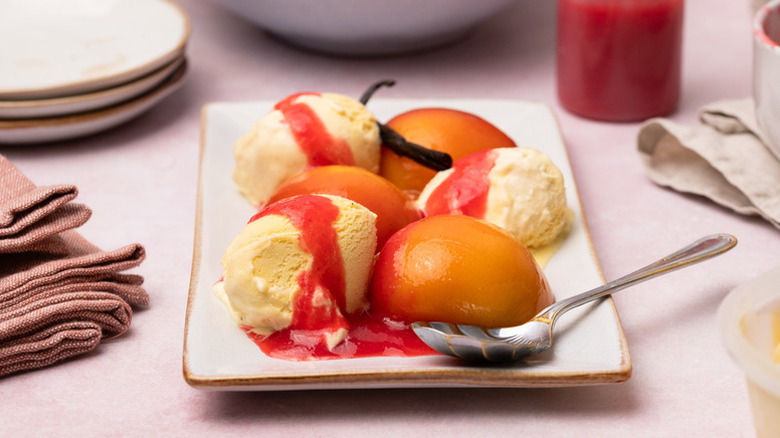 Peach Melba ice cream sundae on serving plate with spoon