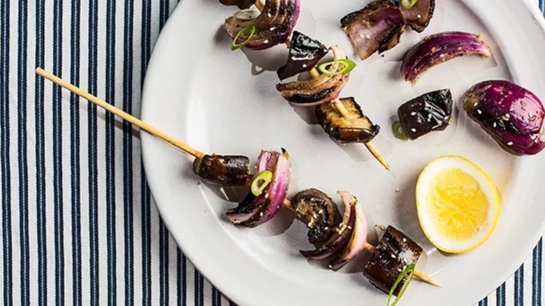 Charred Eggplant-and-Red Onion Skewers on white plate with lemon