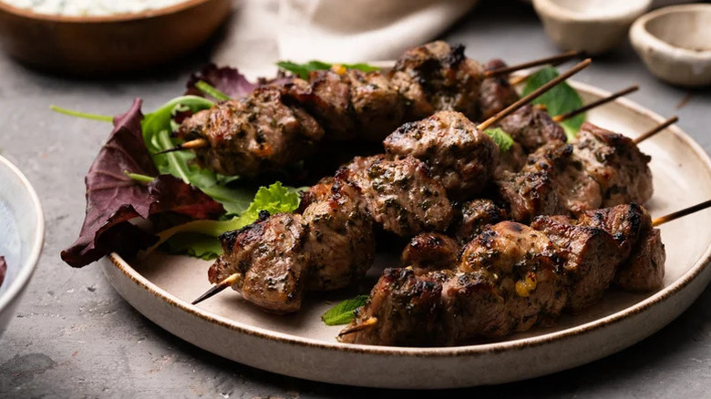 Spiced Honey Mint Lamb Skewers on white plate with salad