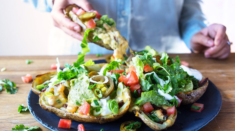 Potato skins on plate, loaded with various nacho toppings