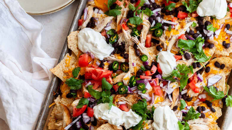 Sheet pan chicken nachos with dollops of sour cream