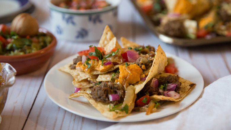 Vegan nachos on plate, topped with carrot-cashew sauce and refried lentils