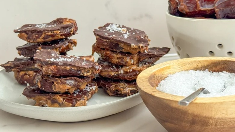 Stacks of chocolatey date bark on a plate next to a bowl of salt