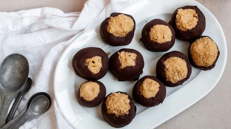 Buckeye candies on a white plate next to a white cloth