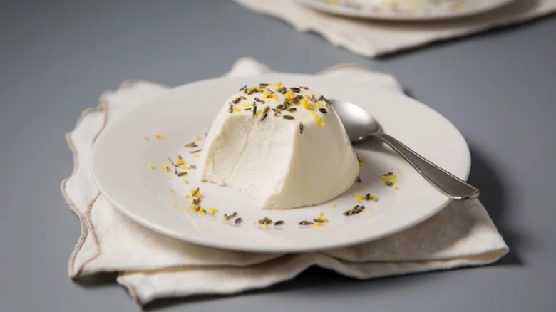 Panna cotta with sprinkles on a white plate with a spoon