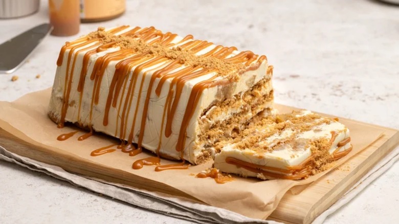 A caramel apple icebox cake partially sliced on a wood board