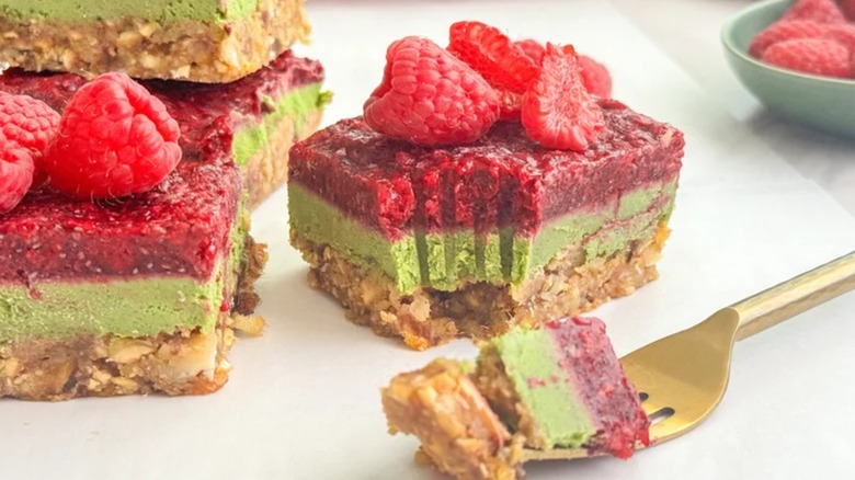 raspberry matcha bars on a white plate with a gold fork