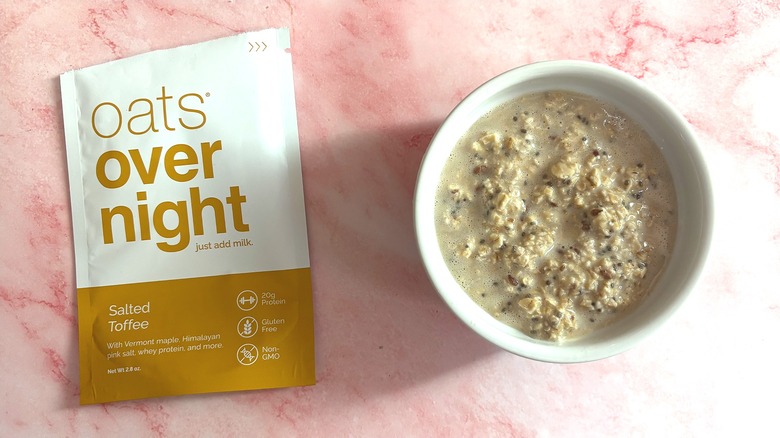 Bowl of Oats Overnight Salted Toffee next to packet on pink surface