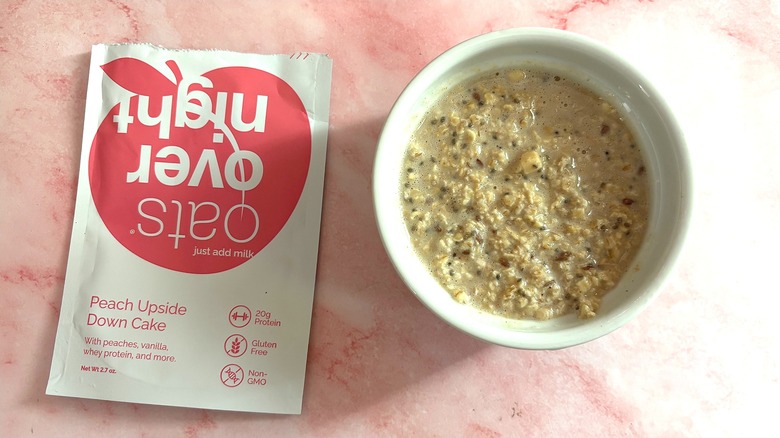 Bowl of Oats Overnight Peach Upside Down Cake next to packet on pink surface