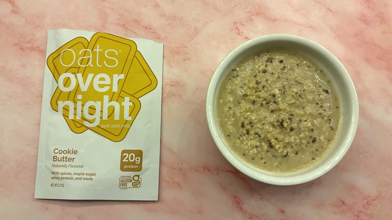Bowl of Oats Overnight Cookie Butter next to packet on pink surface
