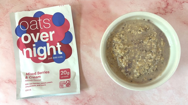Bowl of Oats Overnight Mixed Berries & Cream next to packet on pink surface