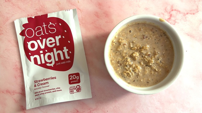 Bowl of Oats Overnight Strawberries & Cream next to packet on pink surface