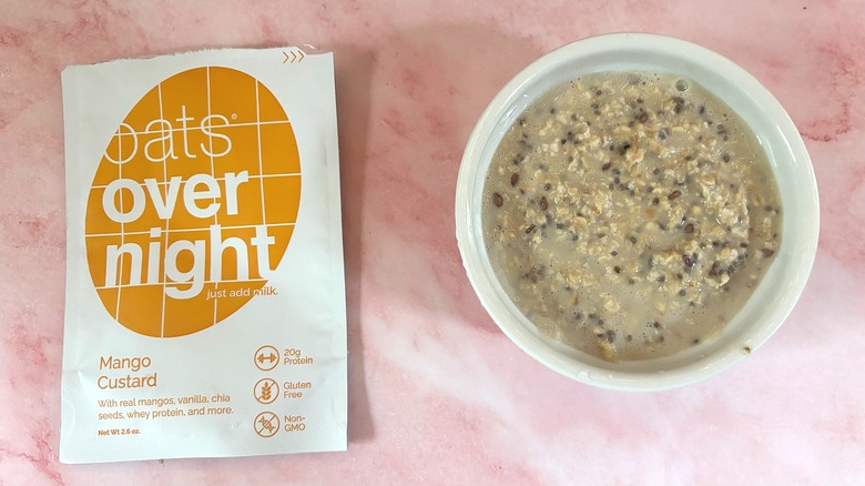 Bowl of Oats Overnight Mango Custard next to packet on pink surface