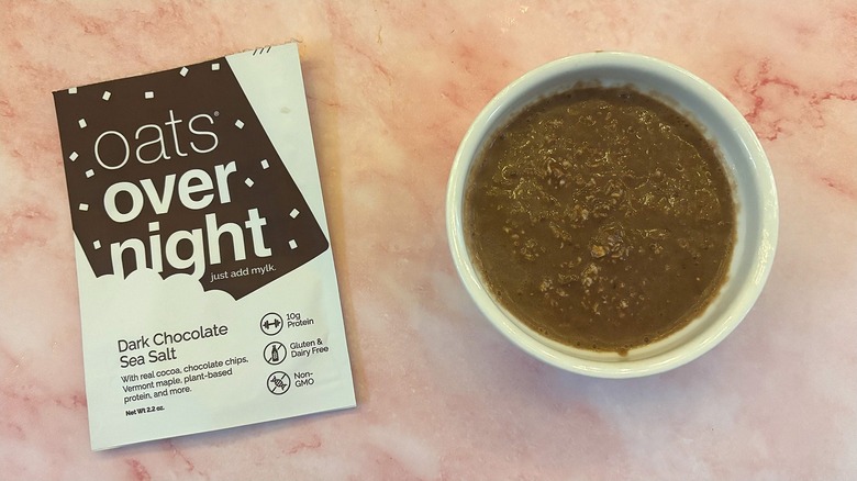 Bowl of Oats Overnight Dark Chocolate Sea Salt next to packet on pink surface