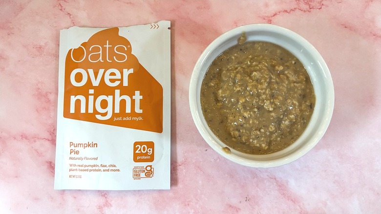 Bowl of Oats Overnight Pumpkin Pie next to packet on pink surface