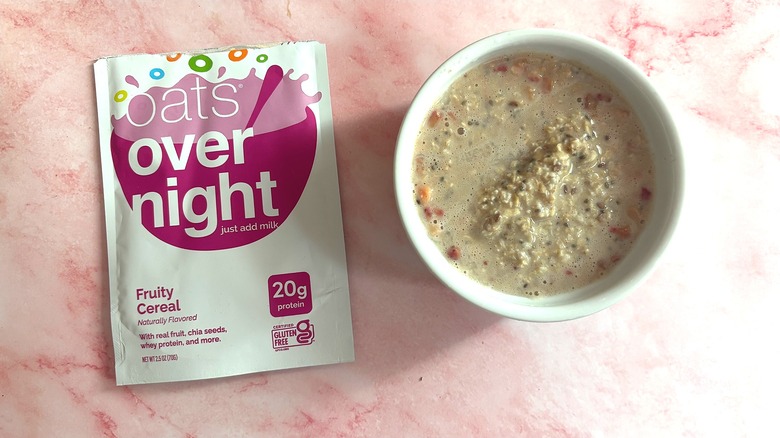 Bowl of Oats Overnight Fruity Cereal next to packet on pink surface