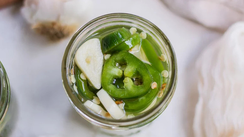 Quick Pickled Jalapeños with garlic in glass jar from above