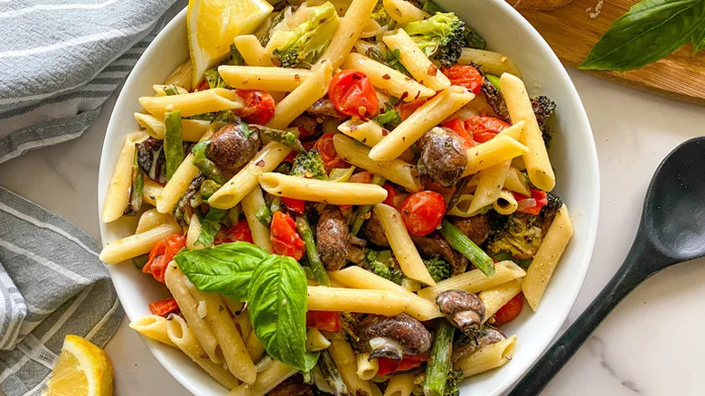 Roasted Vegetable Pasta Primavera in white bowl with black spoon