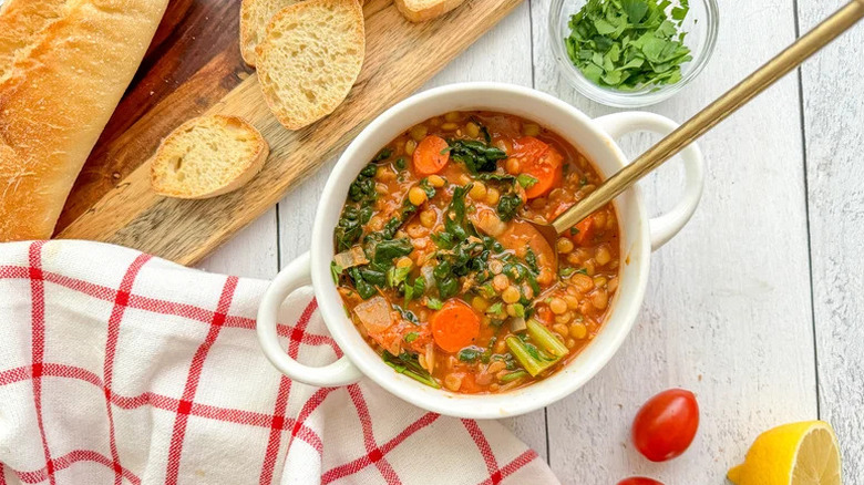 Roasted Veggie and Tomato Lentil Soup in white bowl with gold spoon