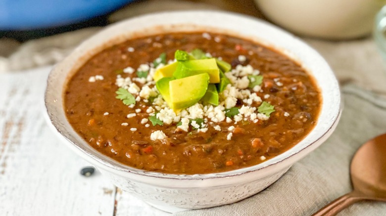 Black bean soup in bowl with avocado slices