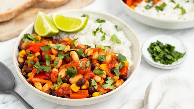 Bean stew in bowl with white rice and lime wedges