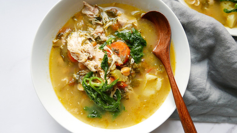 Bowl of chicken and vegetable soup with wooden spoon