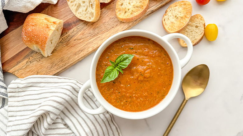 Bowl of tomato soup, garnished with sprig of basil