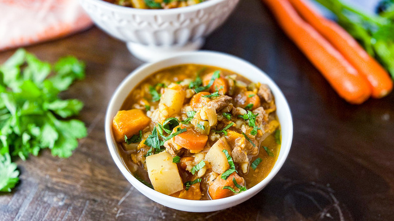 Bowl of beef, vegetable, and barley soup, garnished with fresh parsley