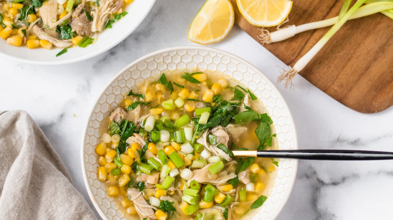 Bowl of chicken and corn soup with green onion garnish