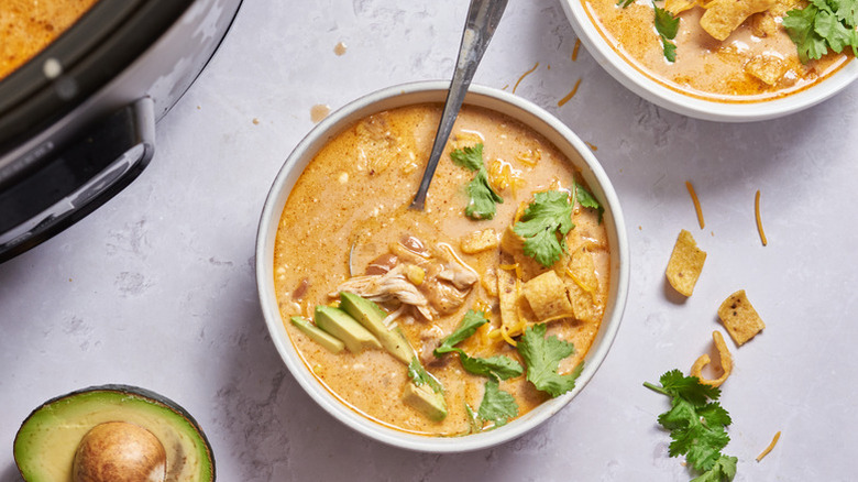 Bowl of chicken enchilada soup topped with cilantro and avocado