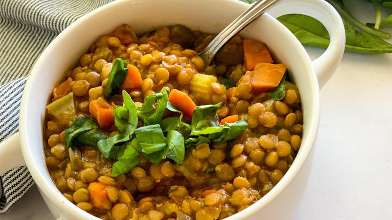 Bowl of lentil and vegetable soup with fresh basil garnish