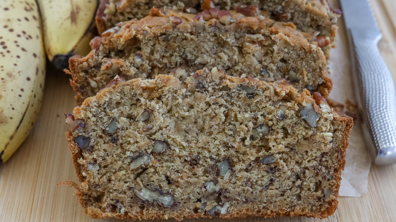 Nut-studded slices of banana bread on wooden board