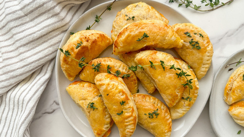Top view of a pile of hand pies on plate, garnished with fresh thyme sprigs